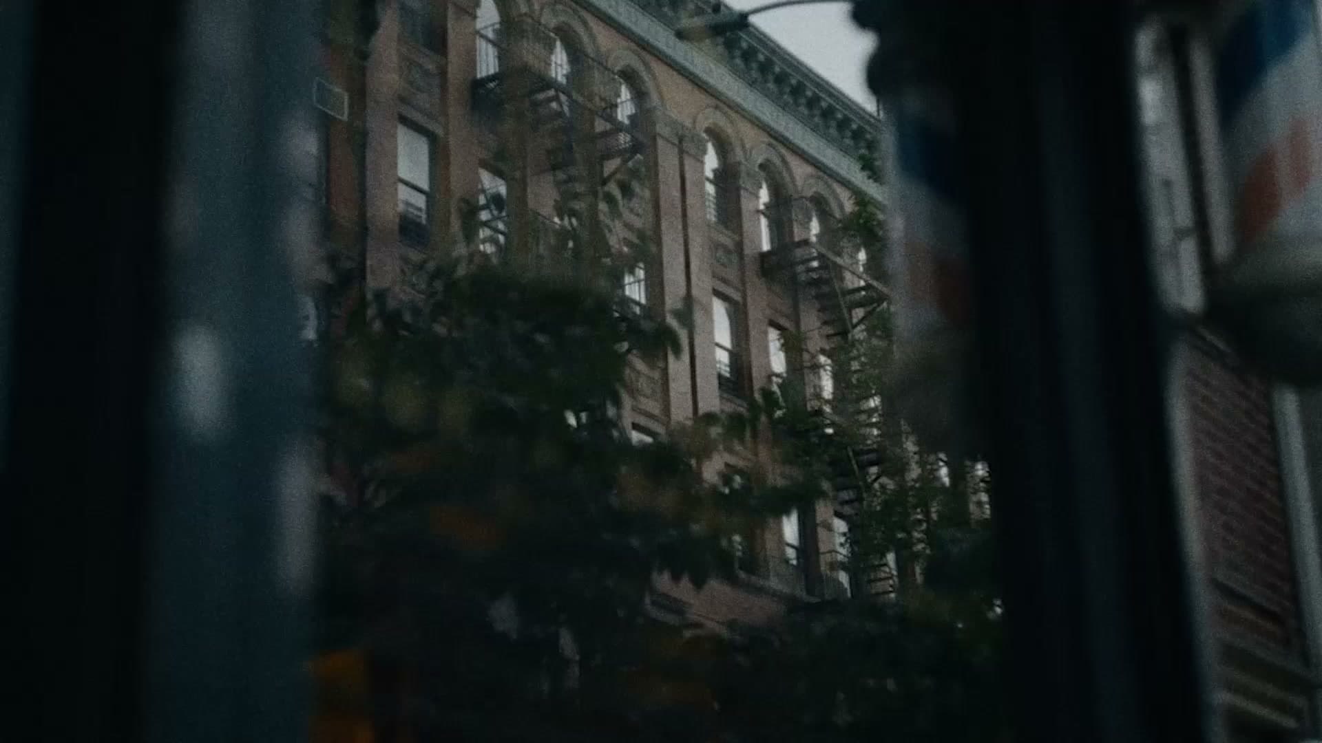 Looking out from Original Barbershop onto an East Village brick building, barber pole in the foreground